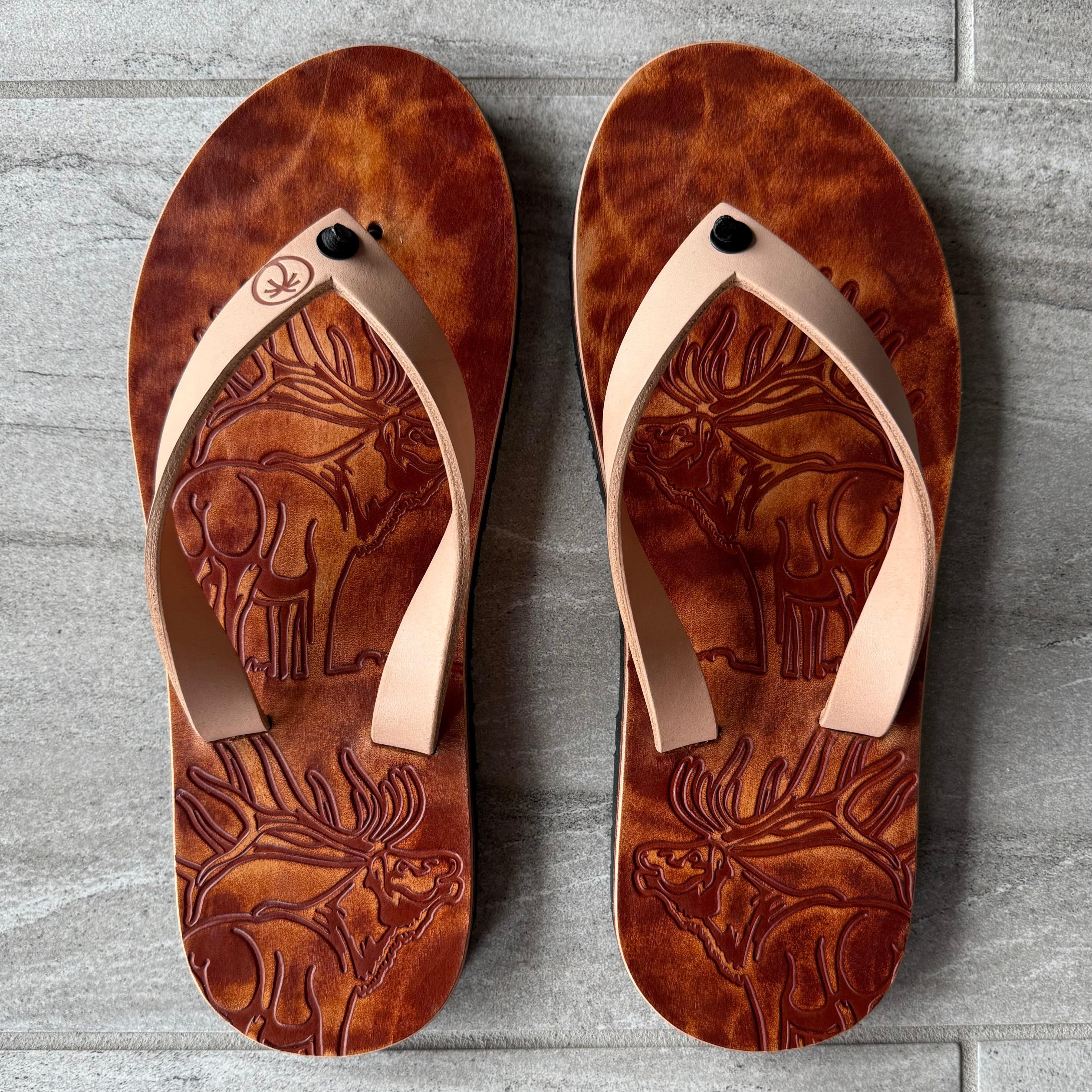 Toehold Bull Elk flip-flops with tan and brown straps featuring a rugged elk design on the footbed.