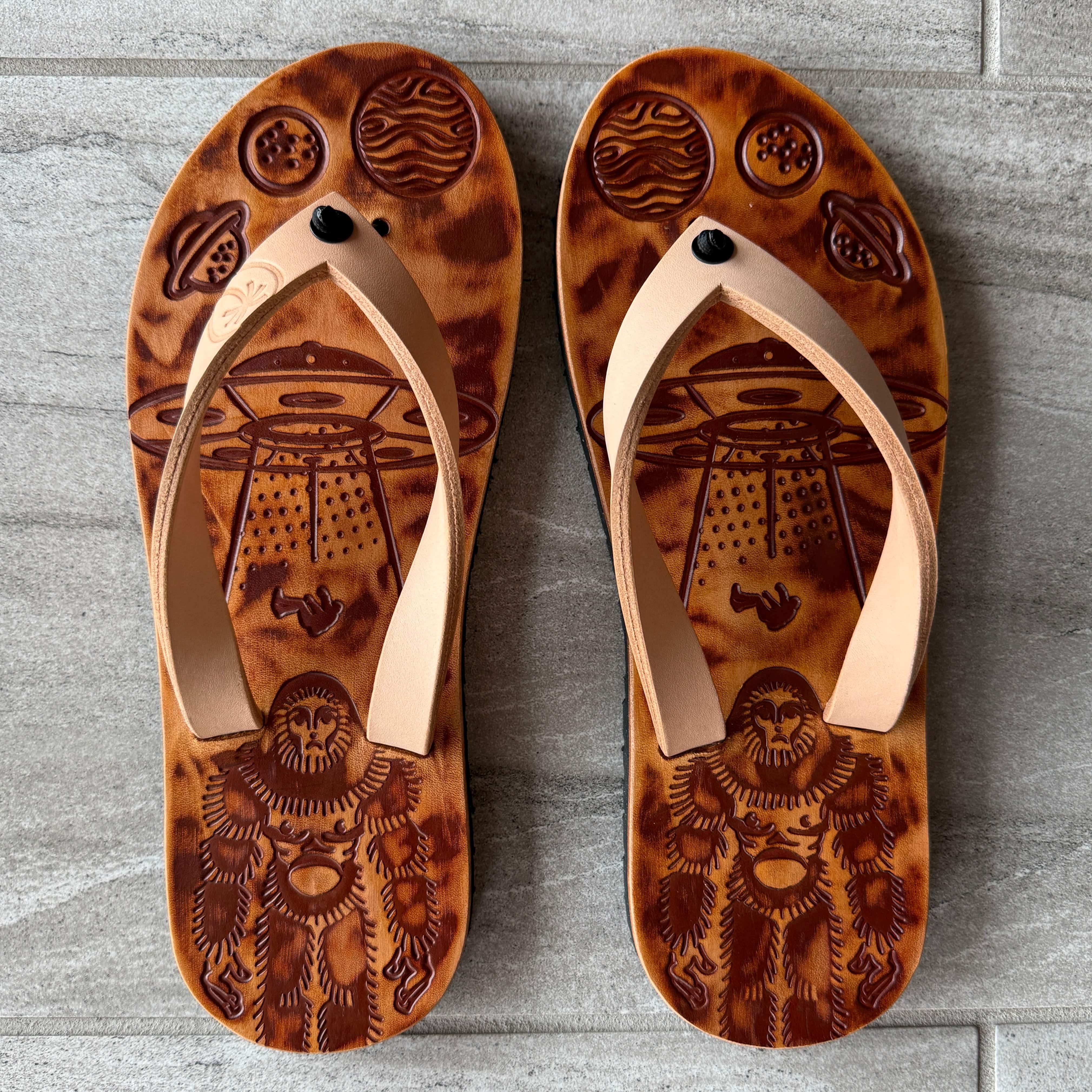 Toehold Bigfoot flip-flops featuring a playful Bigfoot design, with black straps and colorful footbed for casual summer wear.