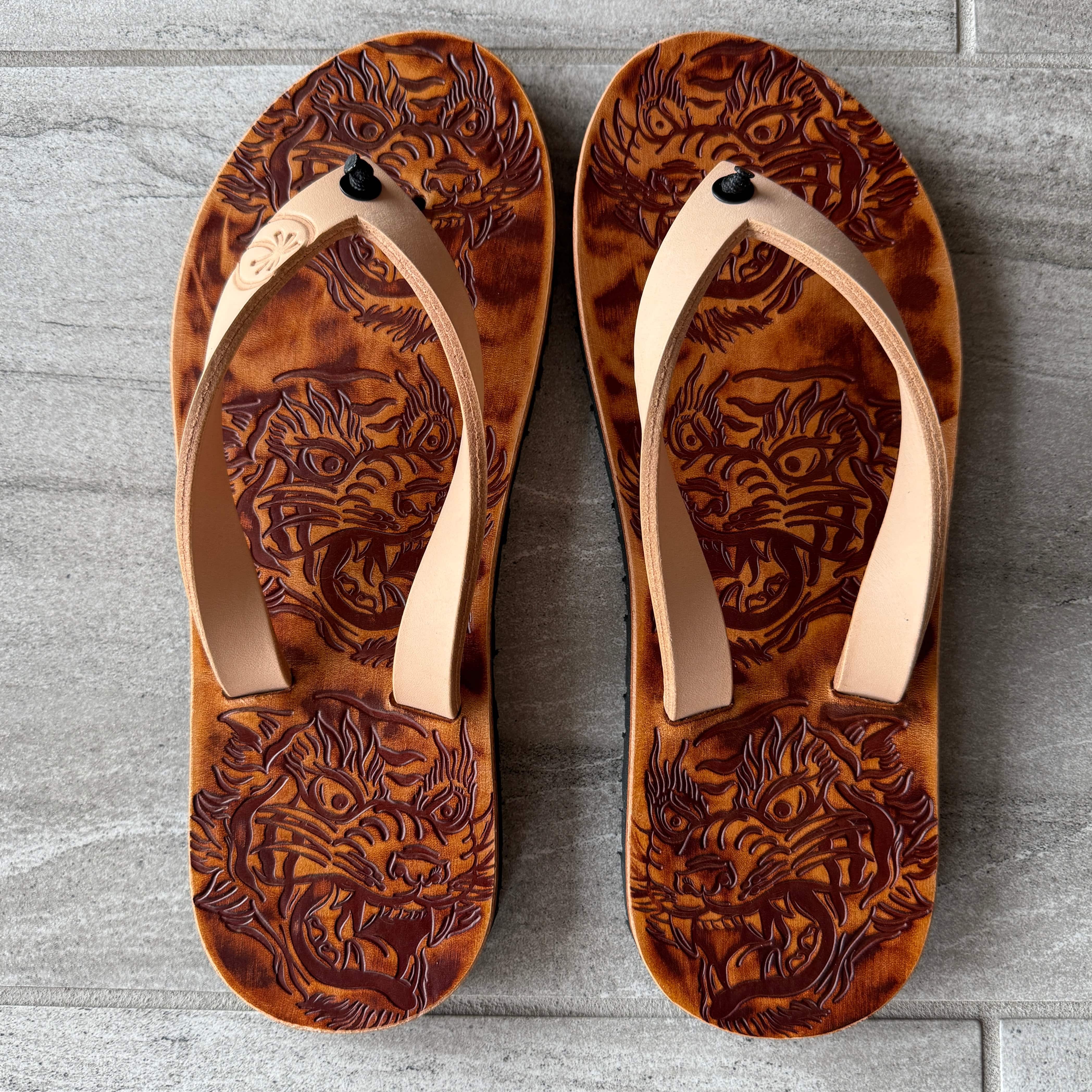 Toehold tiger flip-flops featuring a bold tiger graphic on black rubber soles and straps, perfect for casual summer wear.