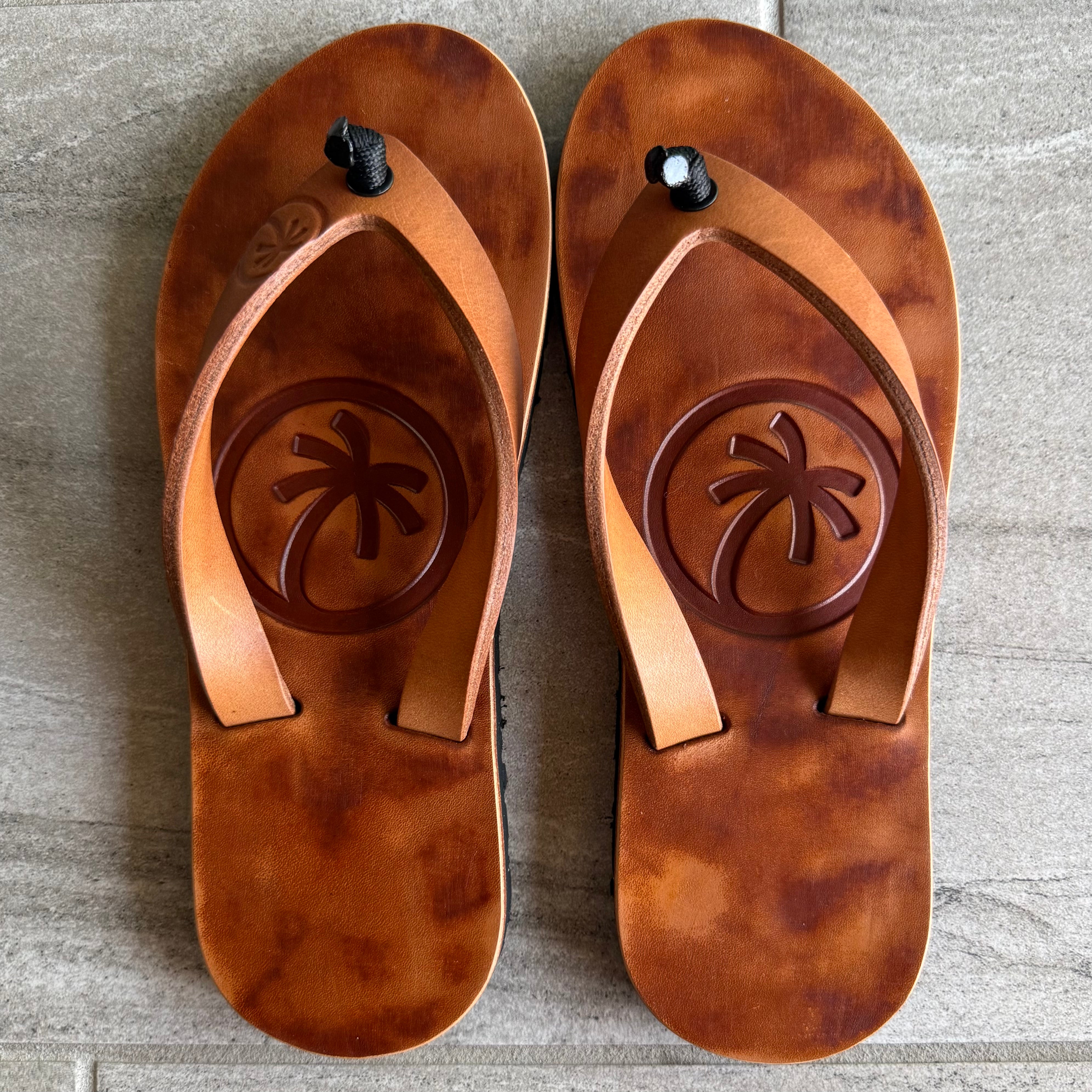 Toehold Classic flip-flops with black straps and beige soles, showing the full view of the casual footwear on a plain background.