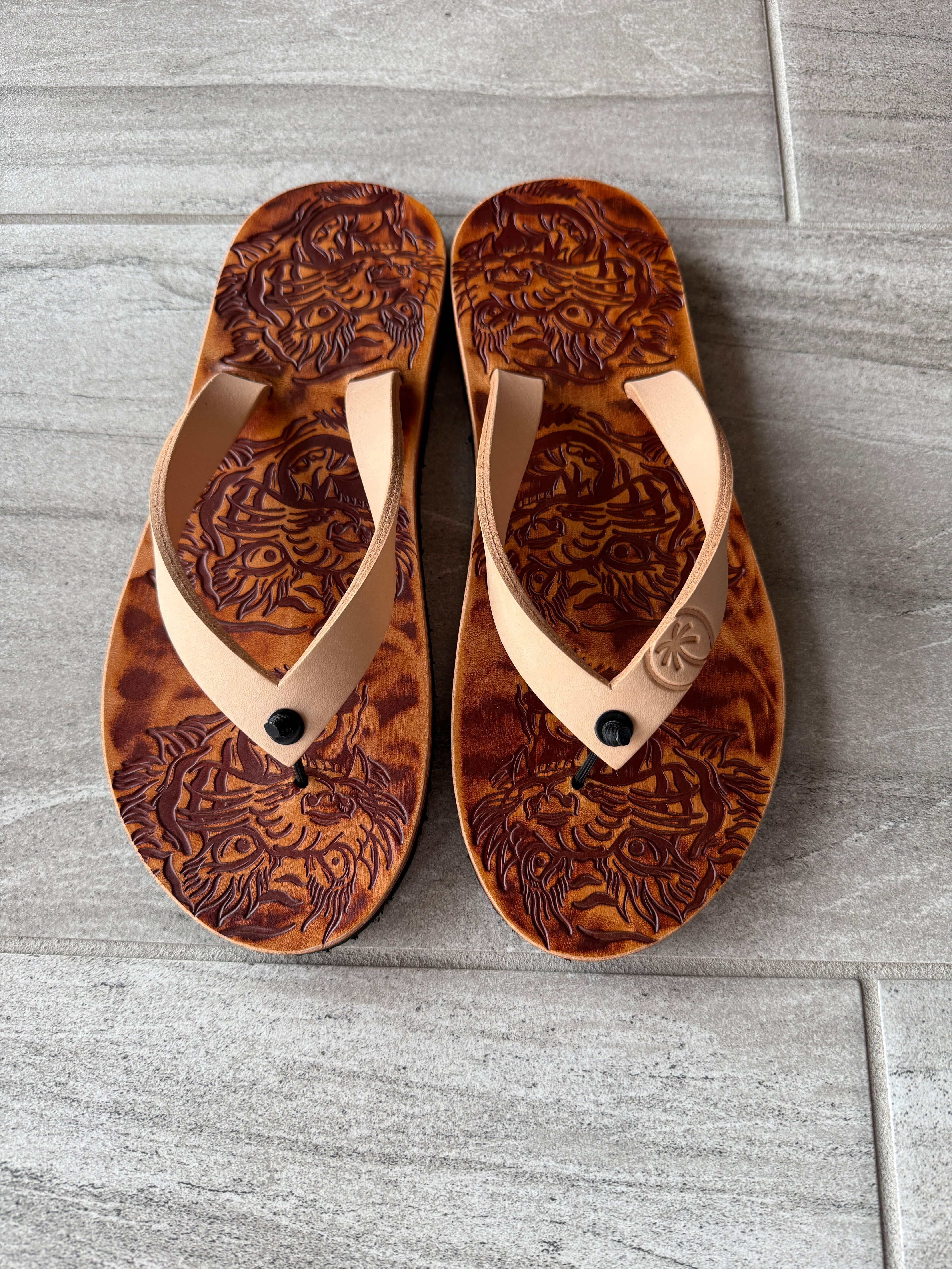 Toehold tiger flip-flops with bold tiger stripe pattern and comfortable straps on a clean white background.