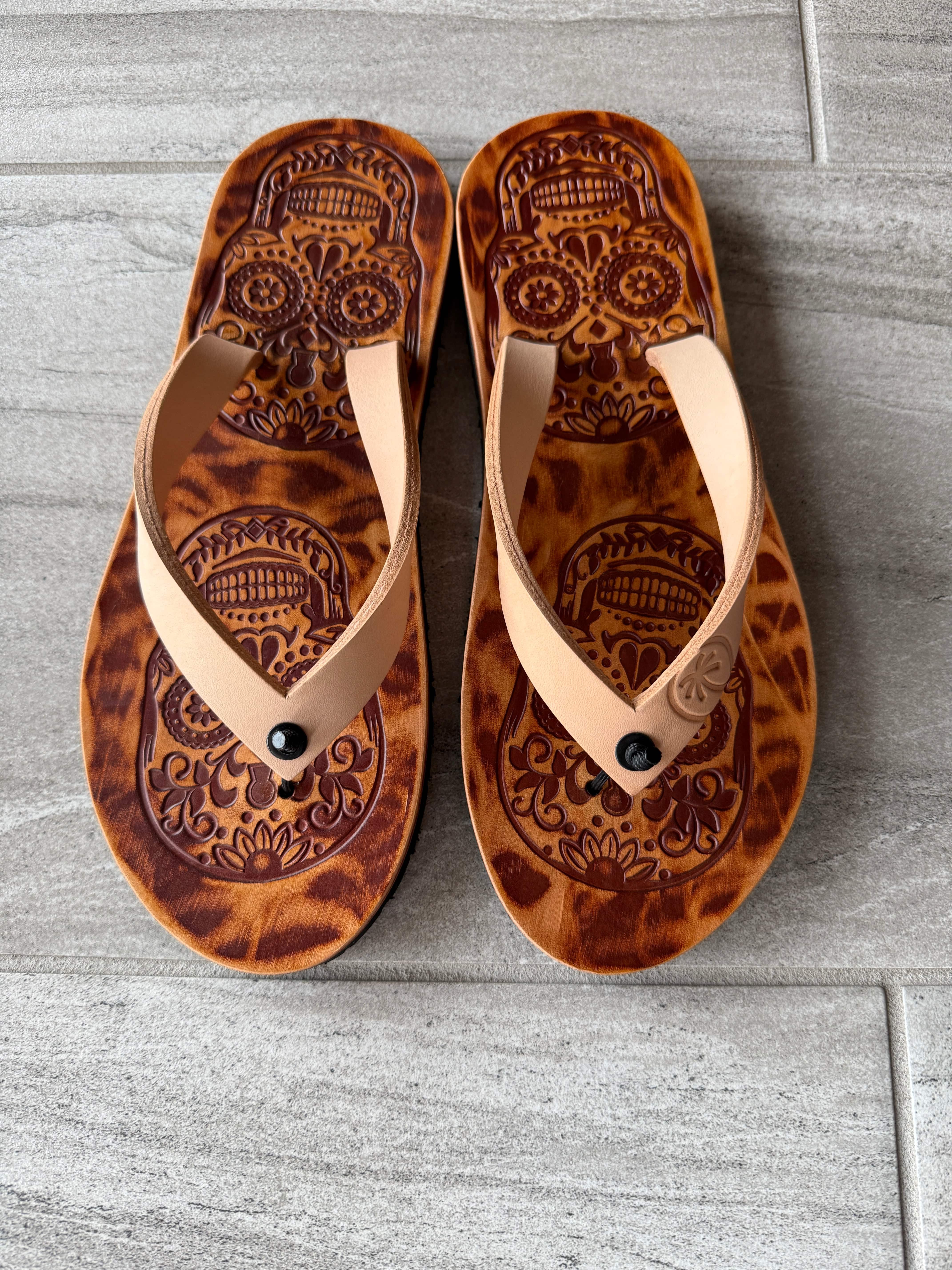 Toehold Skull flip-flops featuring a black and white skull design on the straps and sole.