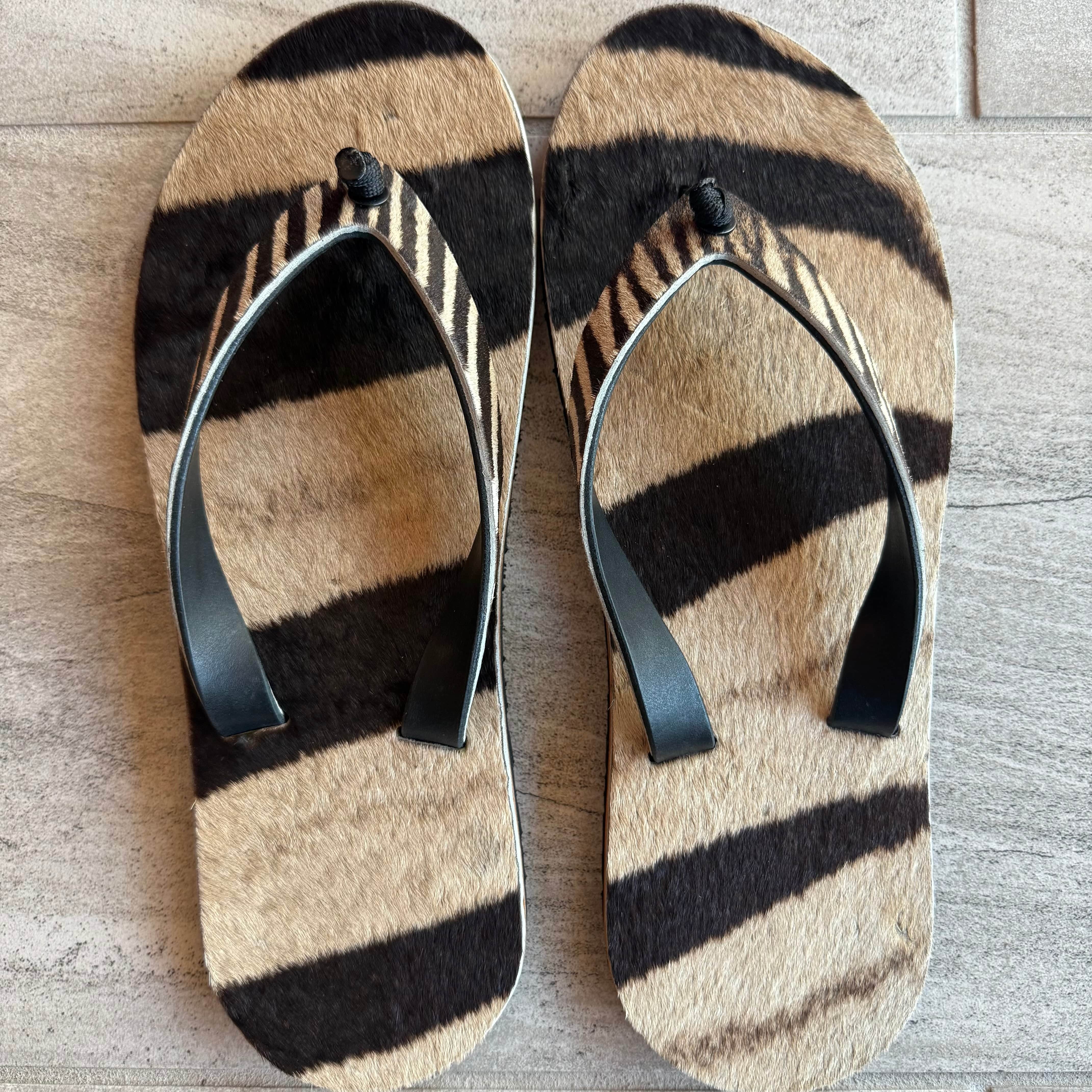 Toehold Zebra flip-flops with black and white striped design, comfortable rubber soles, and casual summer style.