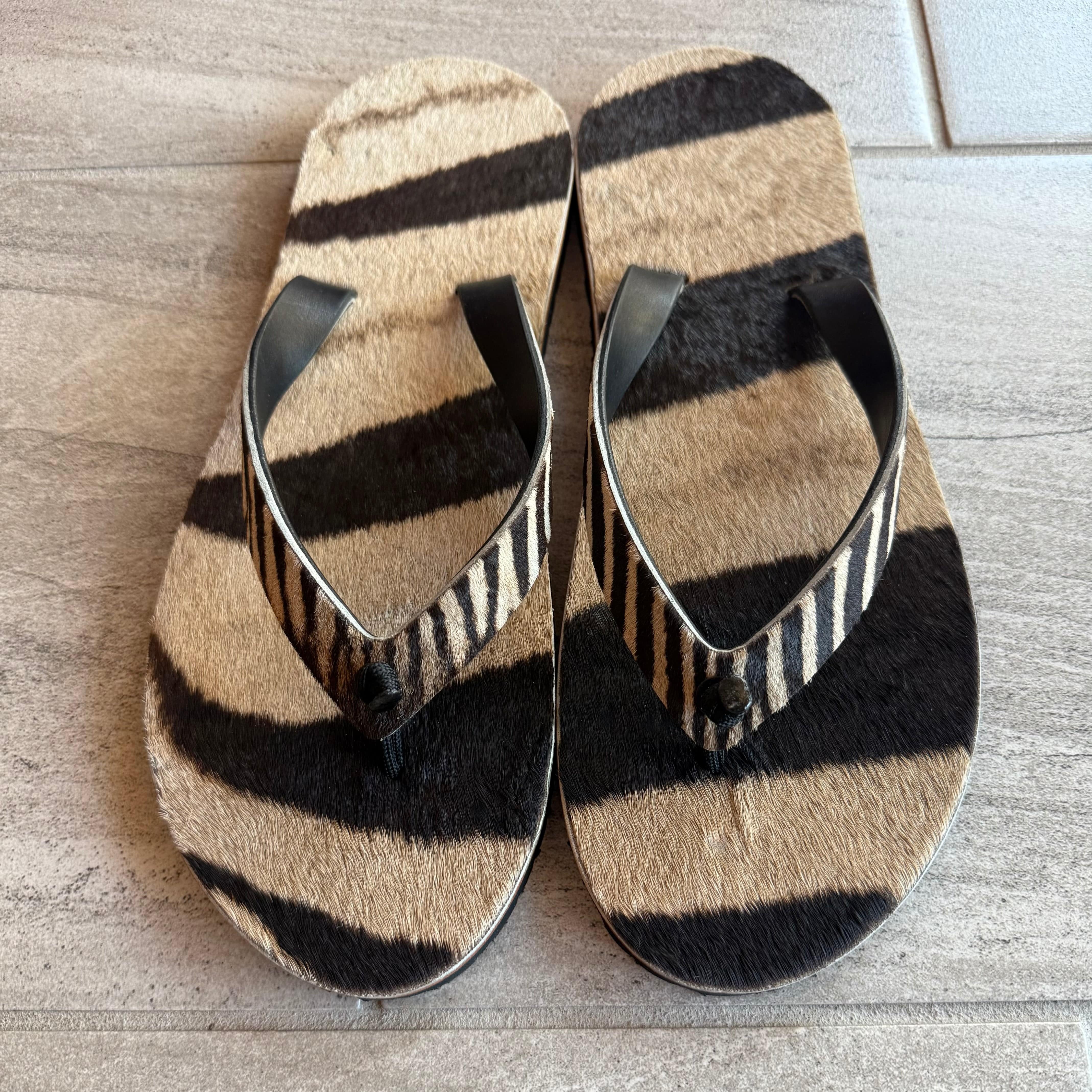 Toehold Zebra flip-flops with black and white striped pattern, casual footwear for warm weather.