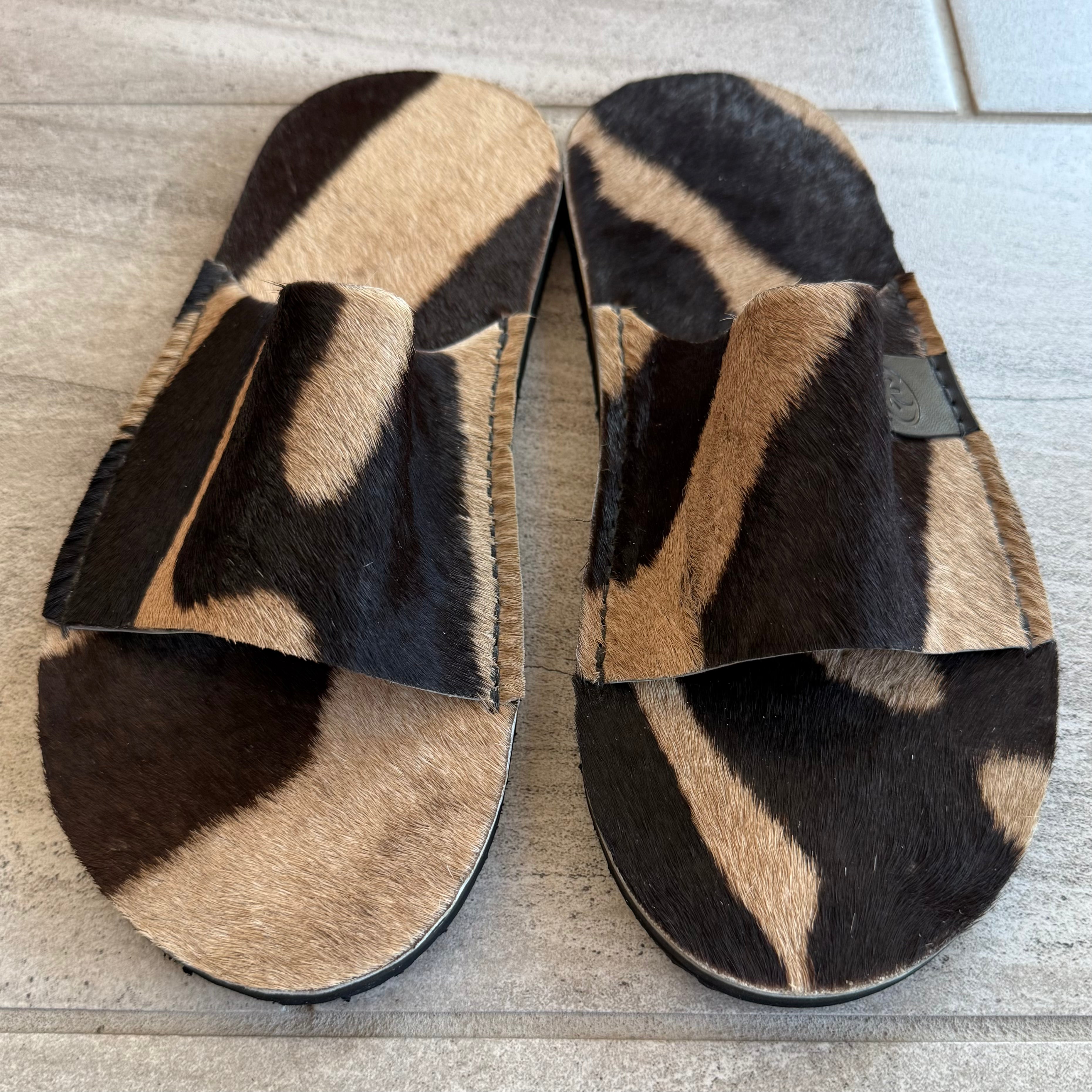 Toehold Zebra Slides featuring black and white zebra print straps on comfortable slide sandals.