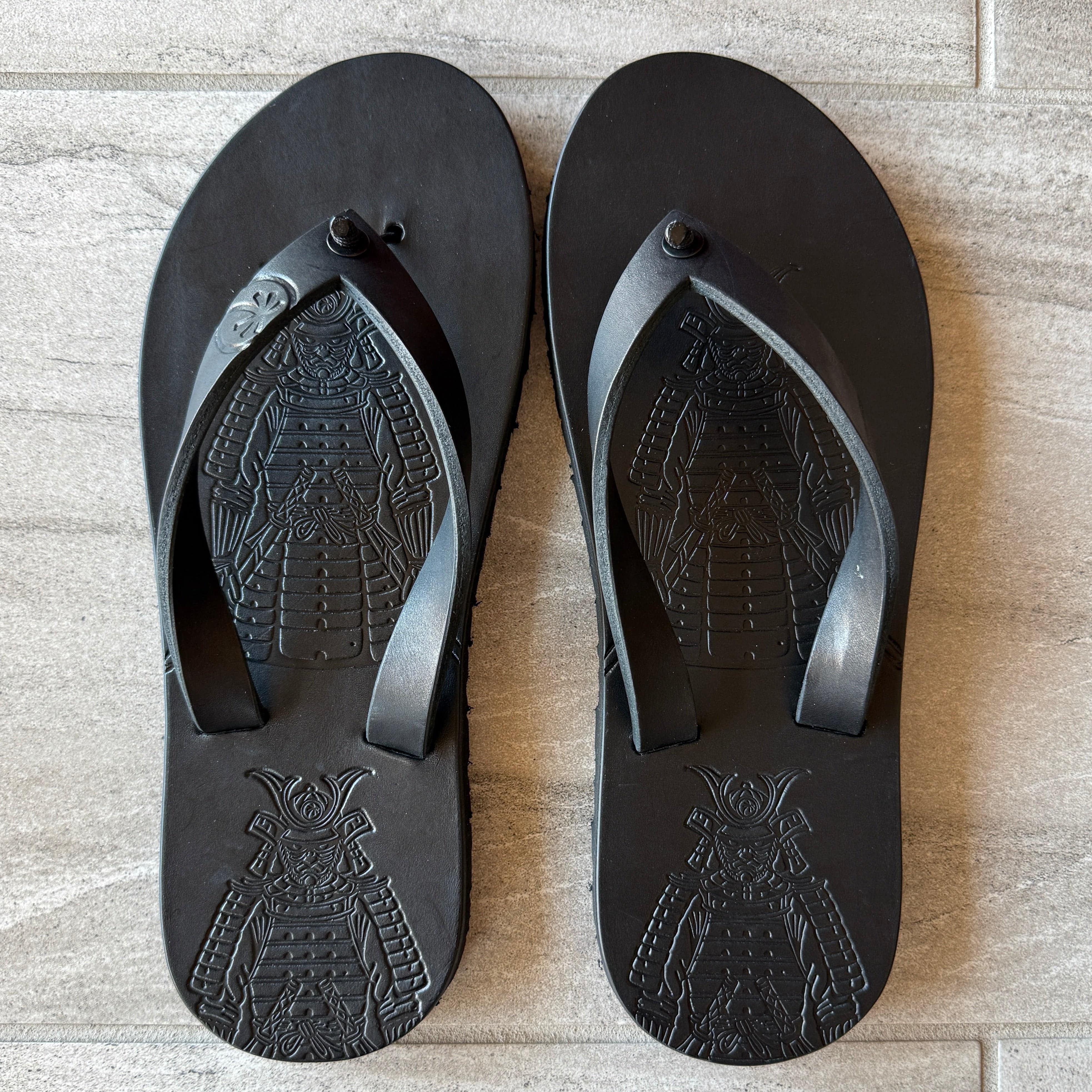 Toehold Samurai Black flip-flops with black straps and textured footbed, displayed on a plain background.