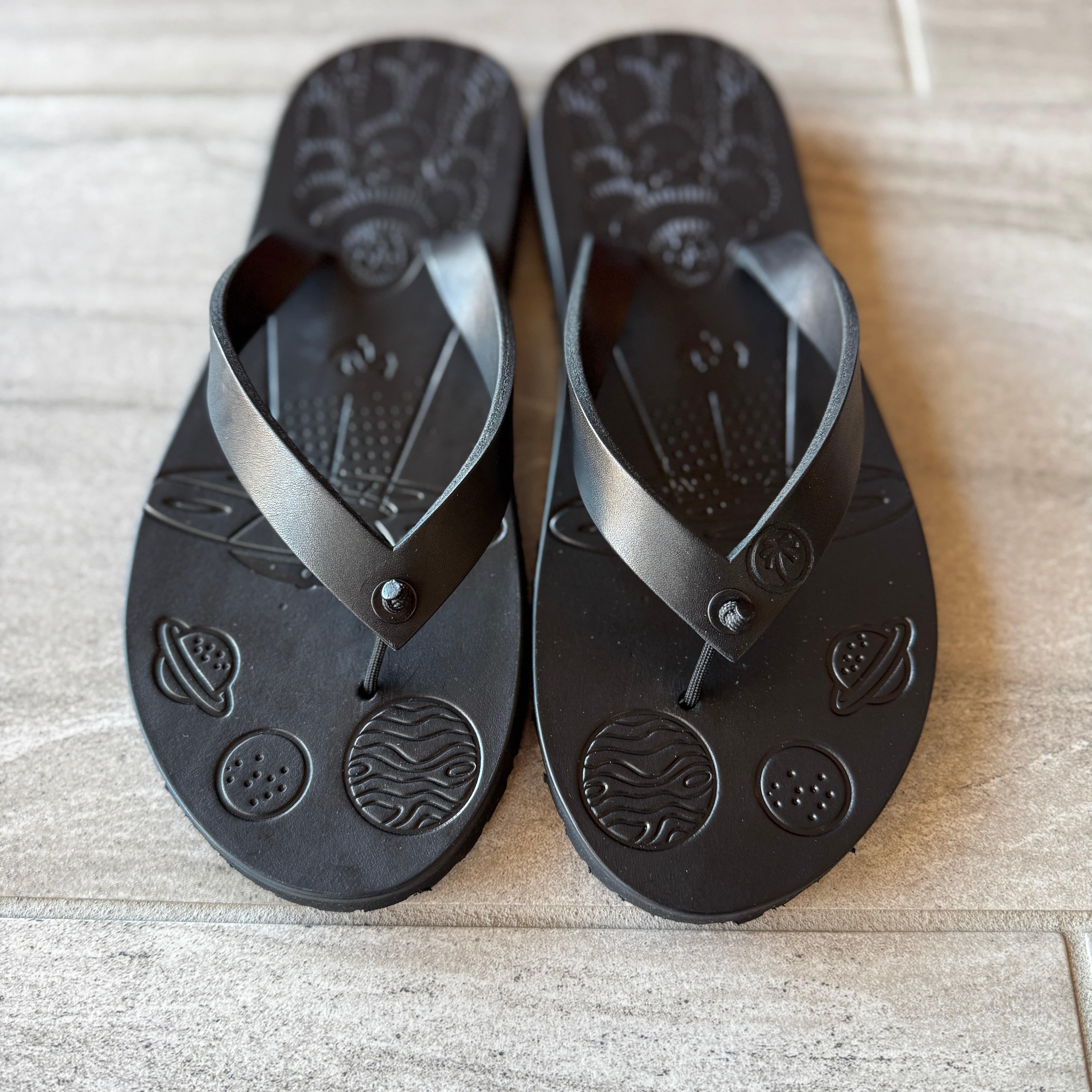 Black Toehold Bigfoot flip-flops with thick straps and textured soles, displayed on a white background.