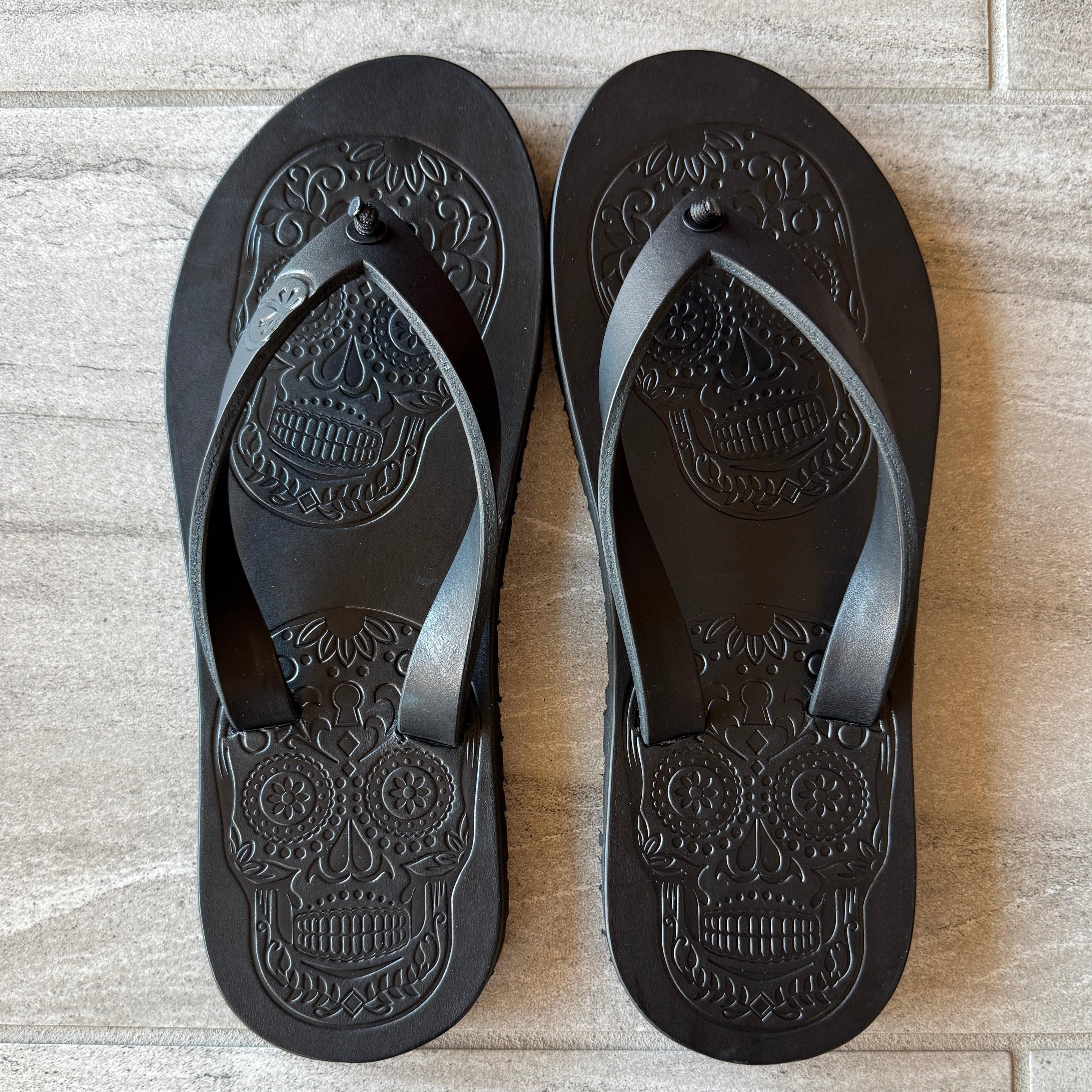 Black Skull flip-flops by Toehold with skull design on the straps, featuring cushioned soles and casual summer style.