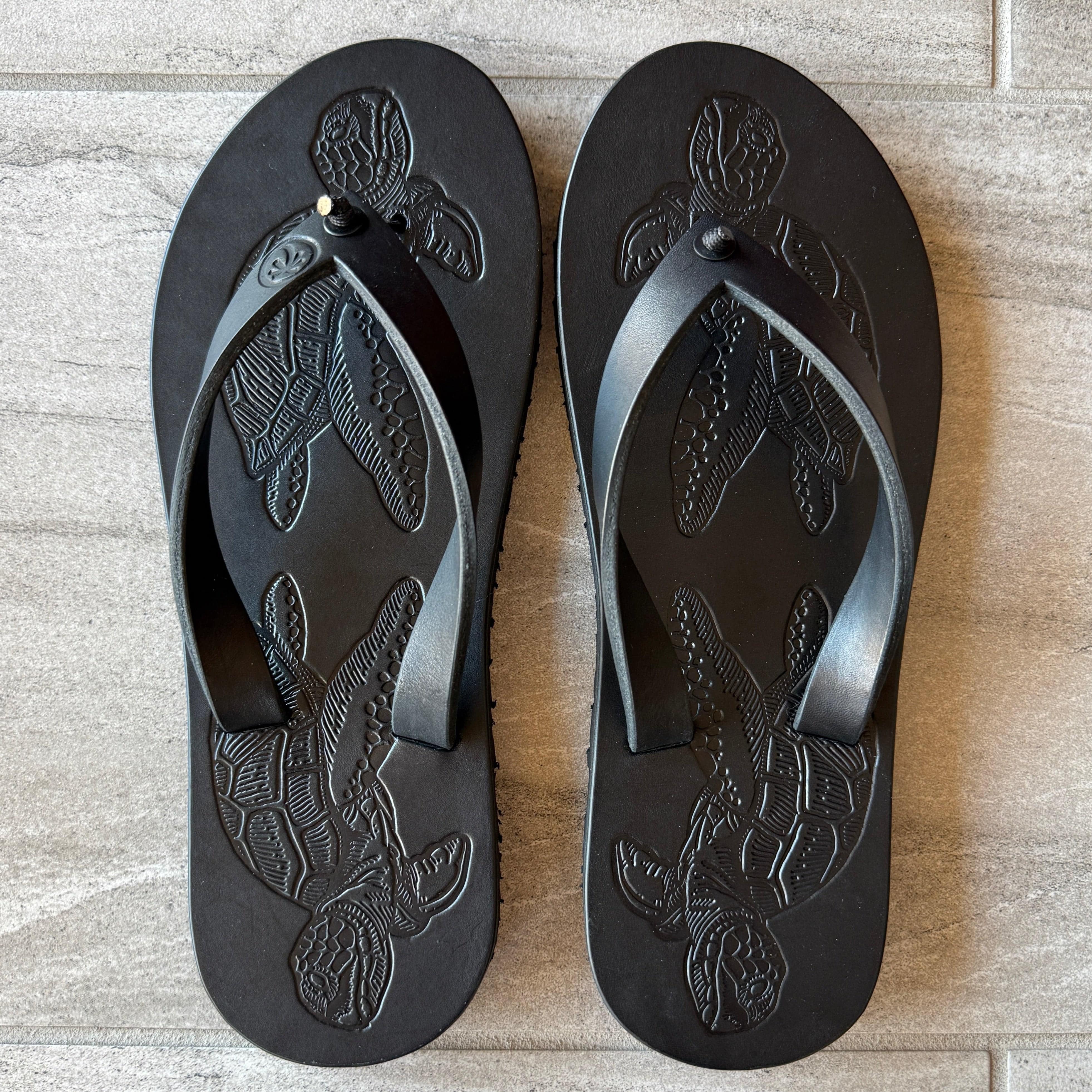 Toehold black sea turtle flip-flops with printed sea turtle design on the straps and soles.