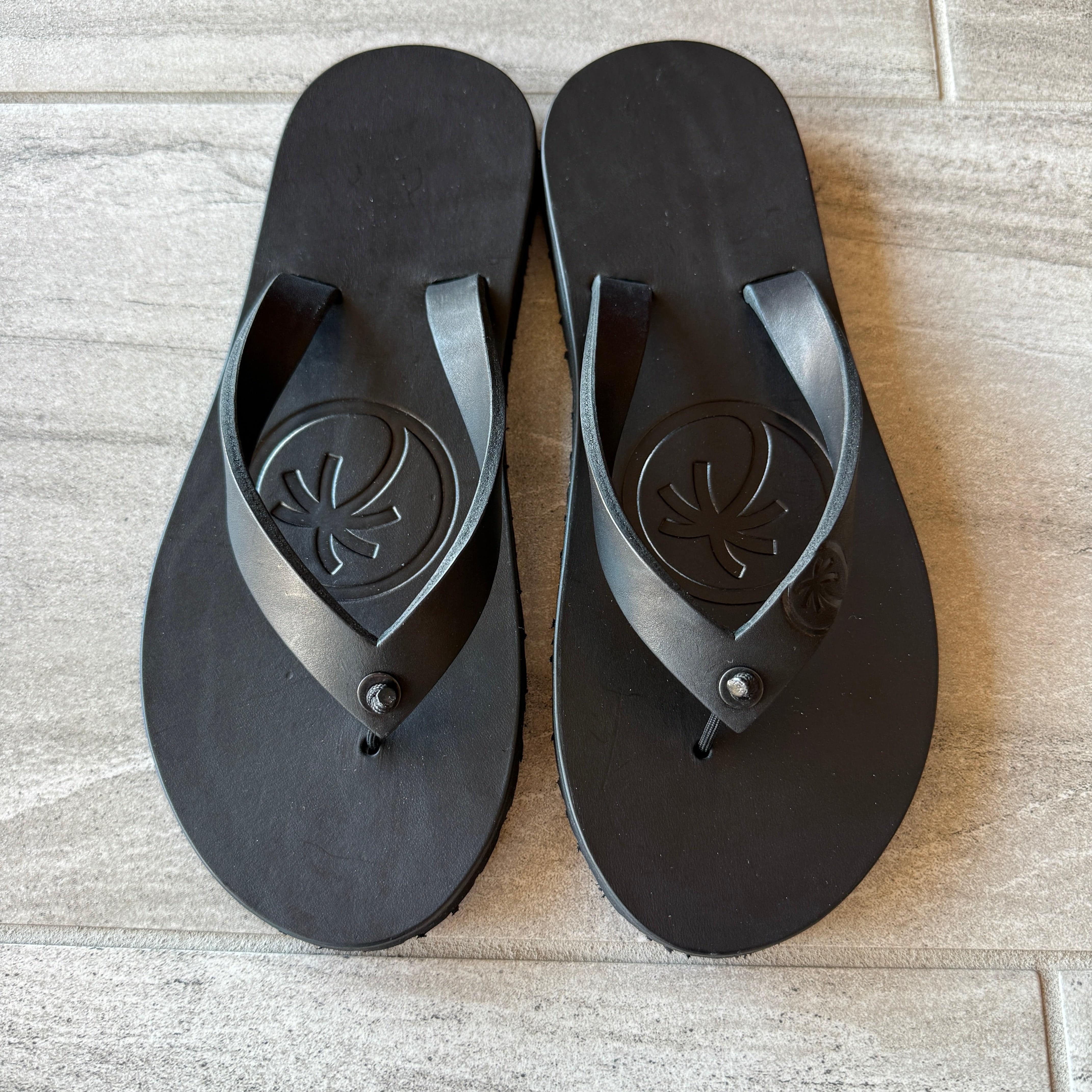 Toehold "Classic" Black flip-flops with black straps and textured footbed, displayed on a plain background.