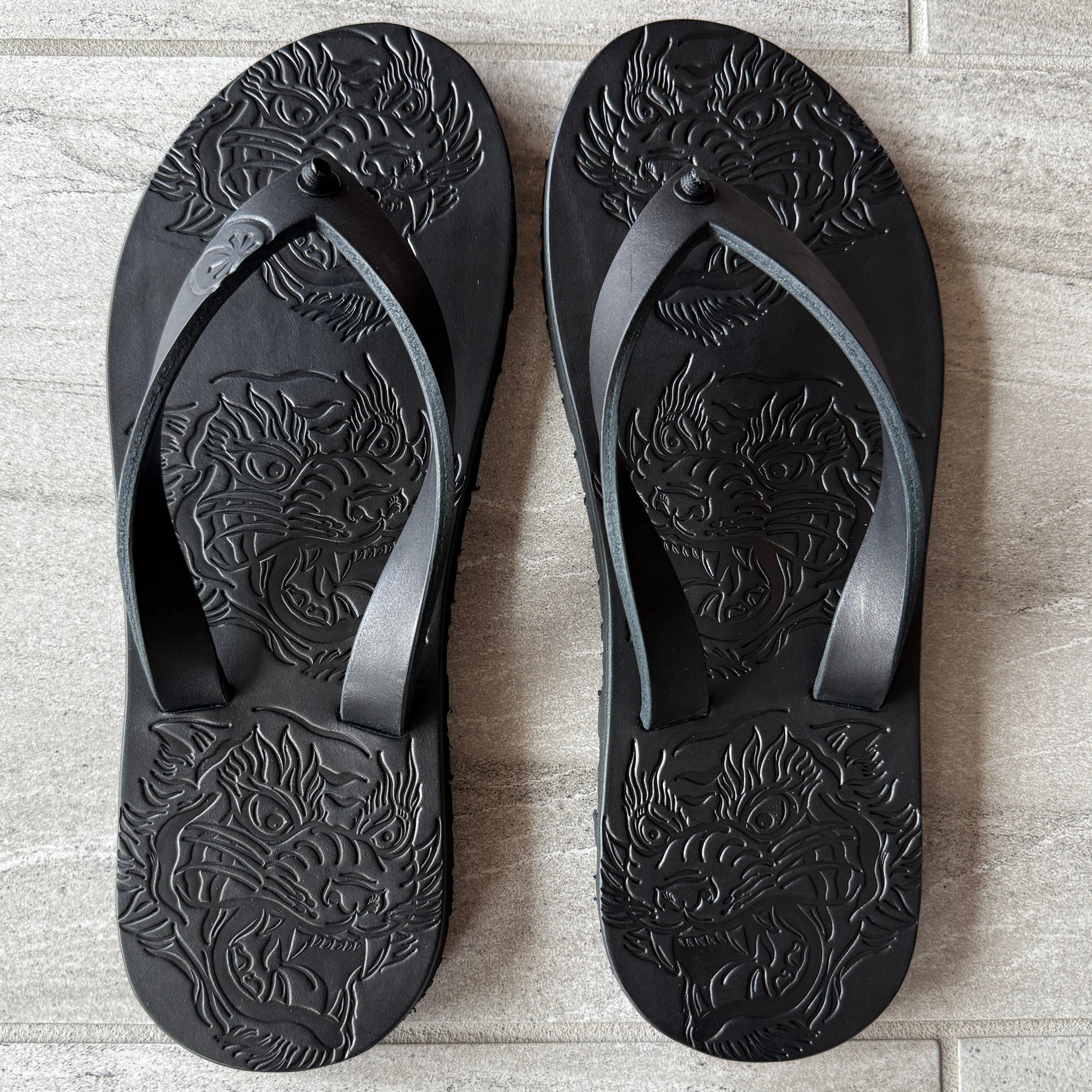Black Toehold "Tiger" flip-flops with textured straps and cushioned soles, suited for casual summer wear.