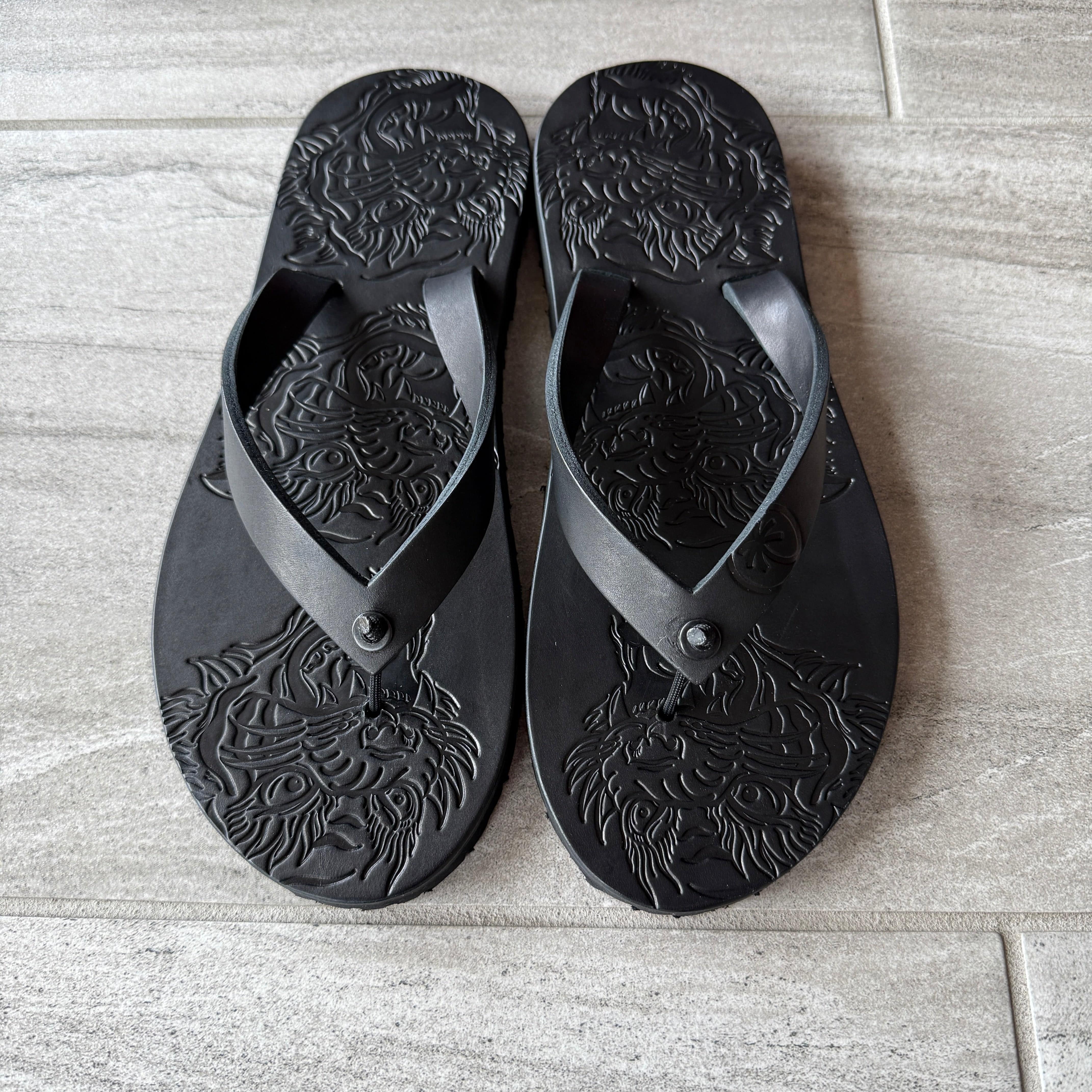 Black Toehold "Tiger" flip-flops with textured footbed and strap design, featuring tiger print accents on the straps.