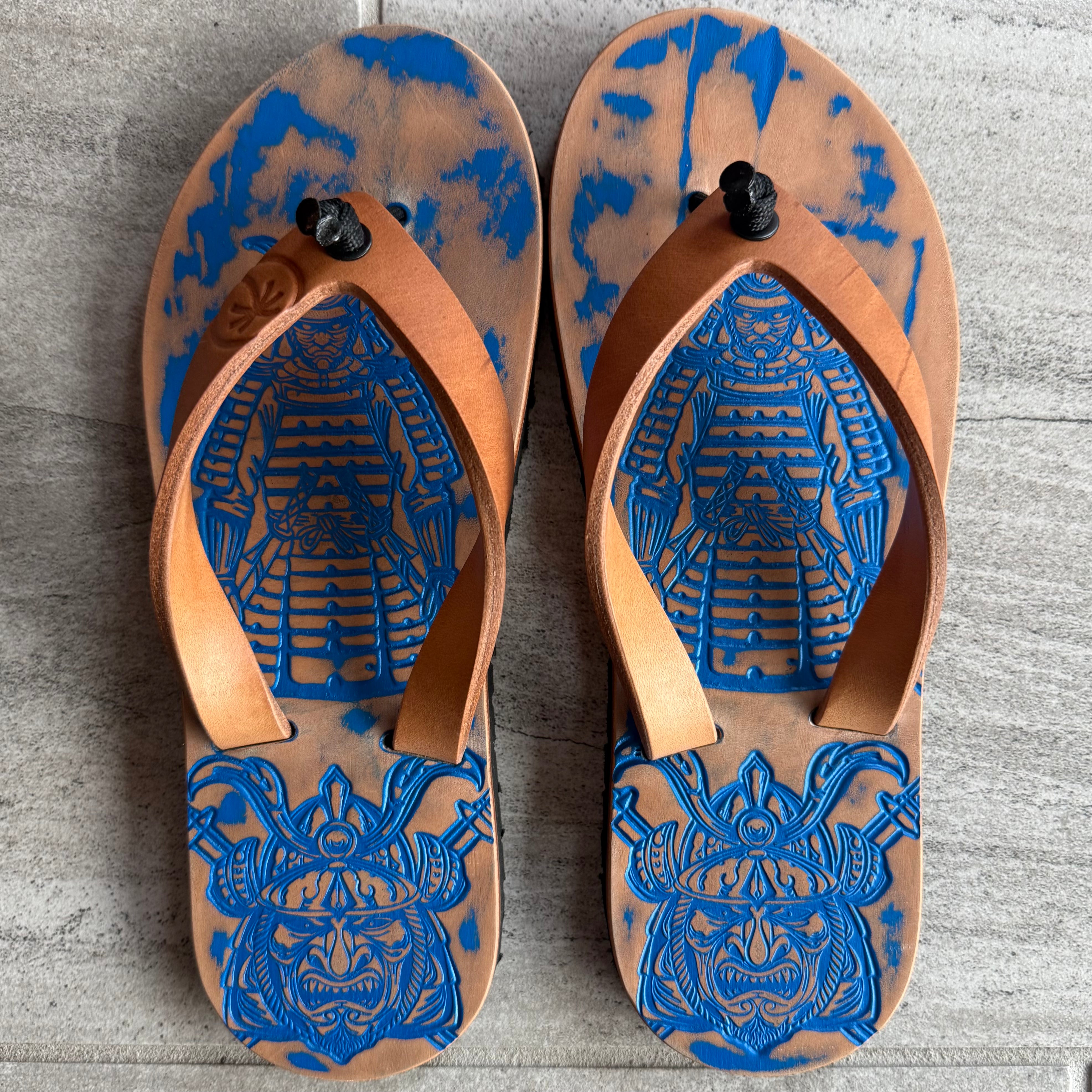 Toehold Royal Samurai flip-flops with black straps and decorative gold accents, shown on a neutral background.