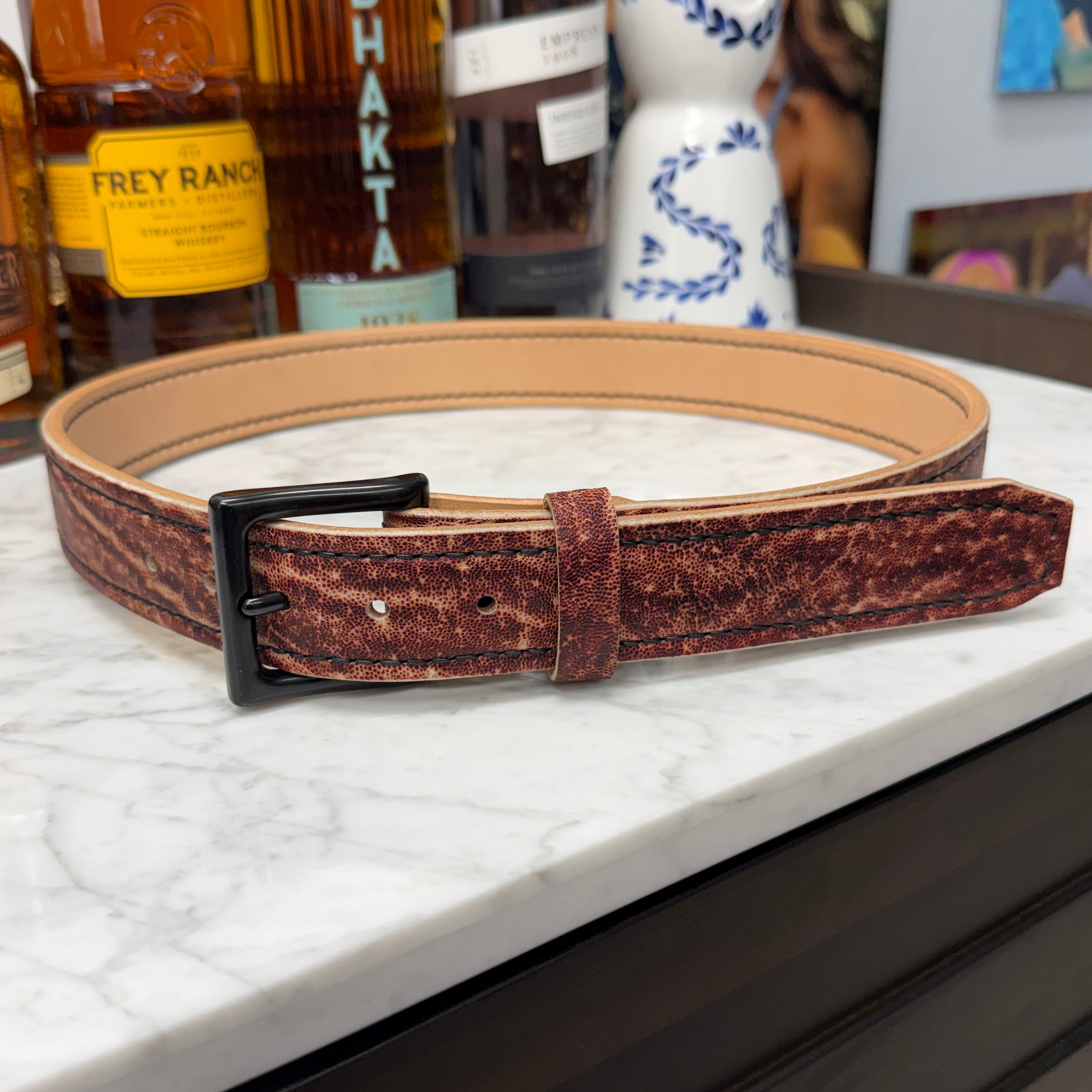Toehold Man Killing Elephant Belt showing detailed leather strap with embossed design and metal buckle.