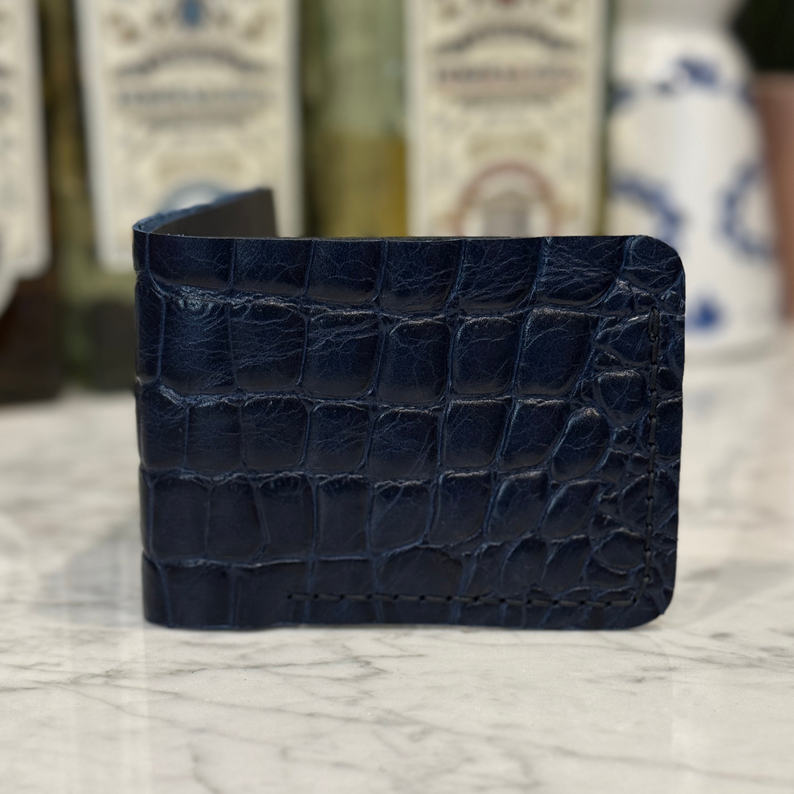 Toehold saltwater crocodile bi-fold wallet showing textured crocodile leather and classic fold design.