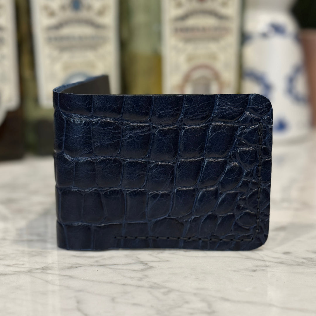 Toehold saltwater crocodile bi-fold wallet showing textured crocodile leather and classic fold design.