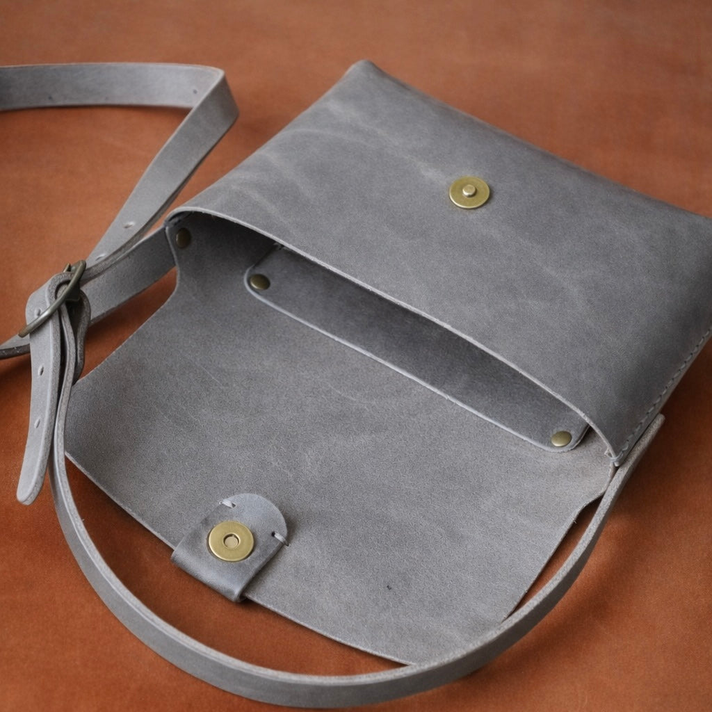 Toehold® Bag featuring a sleek, minimalist design with a leather finish and adjustable strap for versatile style.