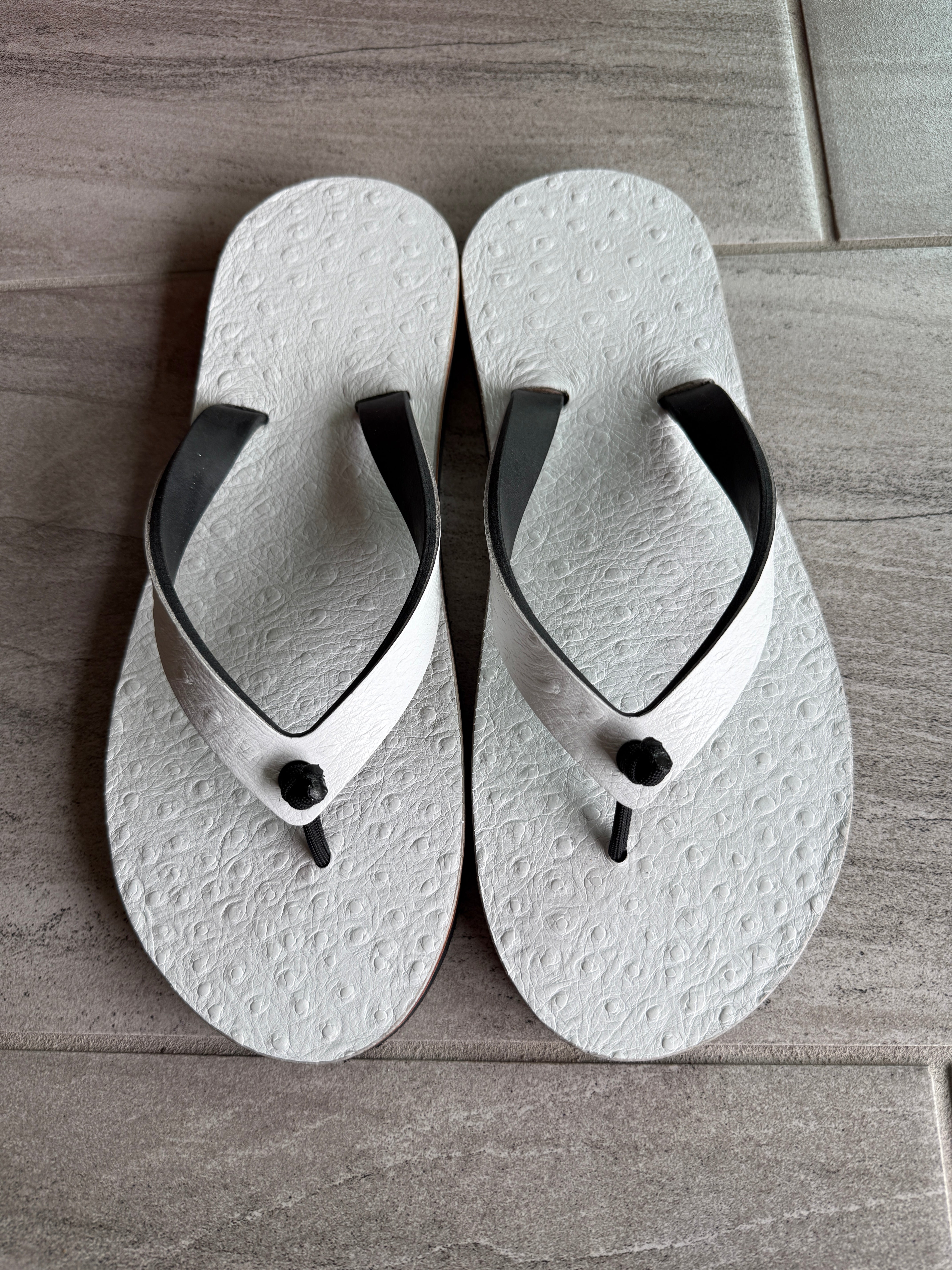 White pressed ostrich flip-flops for women by Toehold with matching straps, showcasing stylish and comfortable footwear.