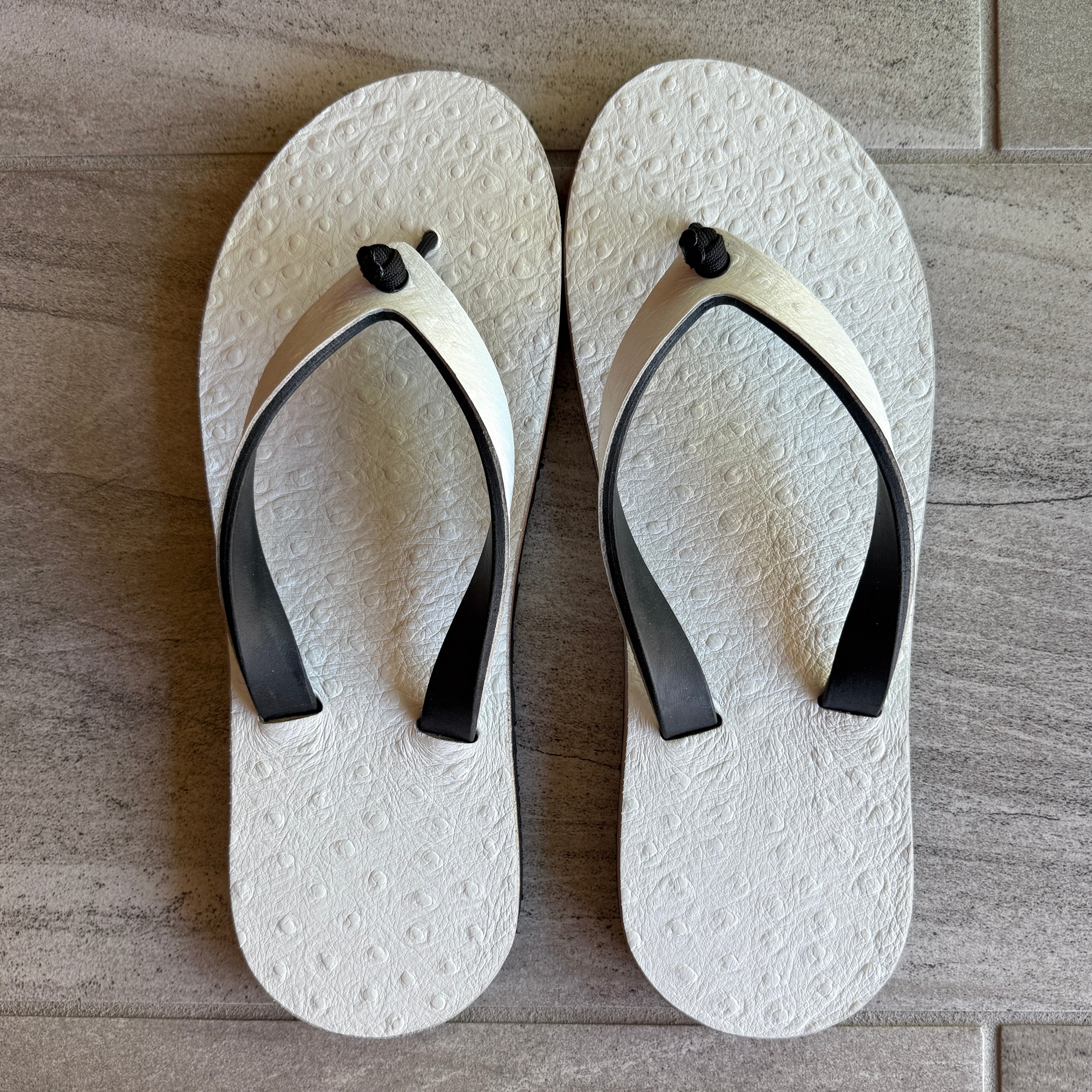 White pressed ostrich flip-flops for women by Toehold featuring matching straps and stylish design.